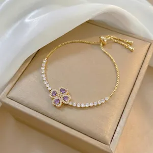Dettaglio di un braccialetto a quadrifoglio dorato con cristalli a cuore viola in un cofanetto