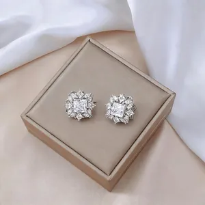 Primer plano de pendientes de flor con circonitas sobre un joyero de color champán