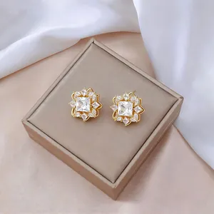 Detalle de pendientes de flor dorada con circonitas en una caja de joyas elegante