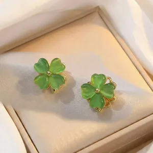 Boucles d'oreilles trèfle oeil de chat vert avec monture dorée sur fond soie