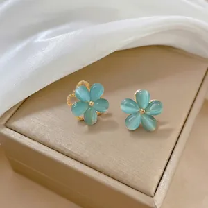 Dettaglio degli orecchini a fiore blu con inserto in zircone su portagioie beige