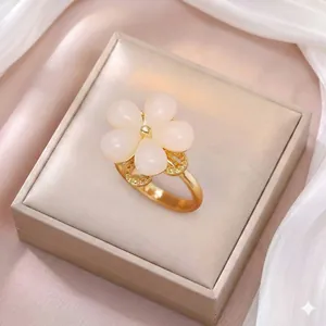 Dettaglio dell'anello dorato a forma di fiore con petali rosa e zirconi su seta