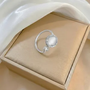 Detail view of a silver open ring with round white gemstone and small zircon accents