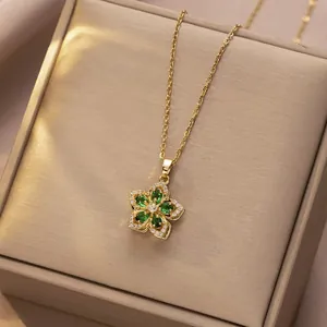 Detailed macro view of rotating green zircon flower pendant on a thin gold chain necklace