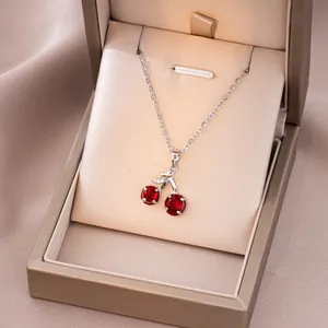 Vue détaillée du collier cerise avec pierres rouges dans son coffret cadeau champagne