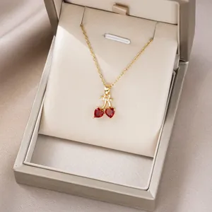 Elegante goldene Kirsch-Halskette mit roten Herzkristallen auf champagnerfarbener Seide