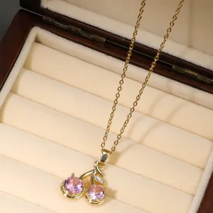 Macro detail of cherry pendant with pink crystals and gold leaf in a velvet jewelry box