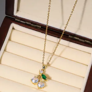 Detail of cherry pendant necklace with white zircon fruits and green gemstone leaf