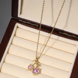 Detailed close-up of cherry pendant necklace with pink heart zircons on velvet jewelry box