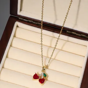 Elegant gold cherry pendant necklace with red heart crystals in a luxury jewelry box