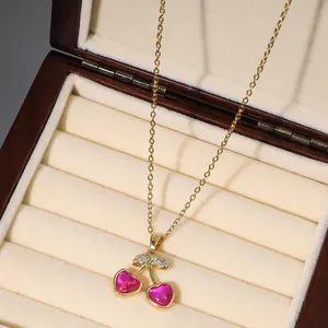 Gold cherry pendant necklace featuring pink heart gemstones and zircons in a jewelry box