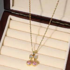 Elegant gold cherry pendant necklace with pink zircon stones and crystal bow on wood box
