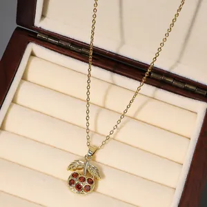 Detailed view of cherry pendant necklace with red cubic zirconia and gold leaves