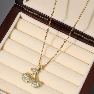 Close-up of a gold cherry pendant necklace with zircon pavé setting in a jewelry box