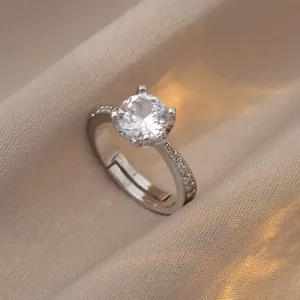 Macro shot of a silver zircon ring with four-prong setting on champagne silk fabric