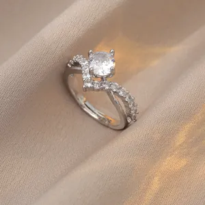 Macro detail of a round solitaire ring with a V-shaped pavé band on silk fabric