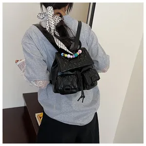 Close-up of black quilted backpack with colorful bead handle on a model back