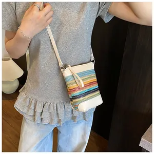 Detail der bunten gestreiften Strohwebung und des cremeweißen Schultergurts der Tasche
