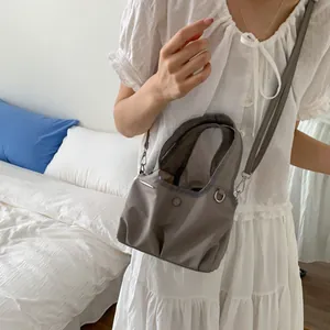 Large capacity nylon tote bag in earthy grey worn crossbody by a model in a bedroom