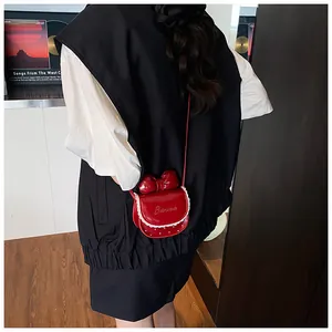 Macro shot of a red patent leather crossbody bag with lace trim and bow on a model