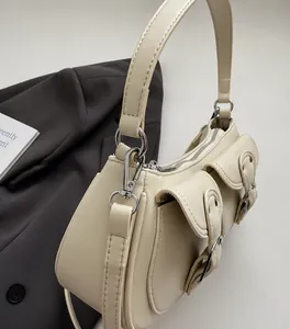 Detalle de bolso de hombro crema con diseño multibolsillos y herrajes plateados