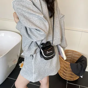 Black glossy crossbody bag with bow and lace detail shown in a lifestyle daily outfit
