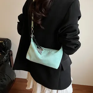 Mint green crossbody dumpling bag with heart charm shown on a black suit model