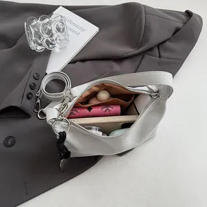 Minimalist light gray suede baguette bag with spacious interior and wide shoulder strap