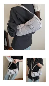 Detalle de un bolso baguette gris claro con bolsillos dobles y hebillas de metal plateado