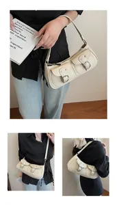 Detalle de bolso de hombro crema con bolsillos utilitarios dobles y hebillas de metal