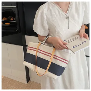 Detail view of striped canvas tote with leather straps and colorful webbing handles