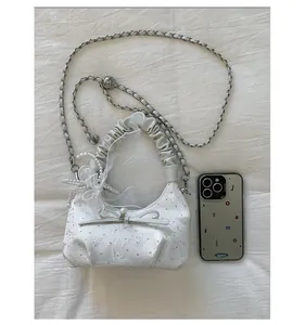 Detail of white embroidered shoulder bag with pearl bow and褶皱 handle for scale