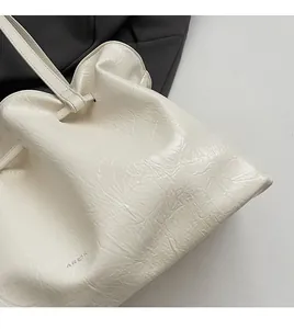 Detailed close-up of white pleated oil wax leather texture and logo on shoulder bag