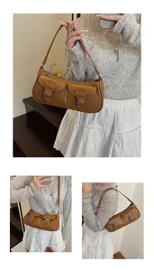 Detalle de un bolso baguette marrón vintage con bolsillos frontales y hebillas