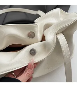 Detail of magnetic buckle closure and pleated texture on cream shoulder tote bag