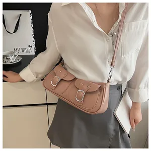 Detalle de bolso de hombro rosa palo con bolsillos dobles y hebillas plateadas