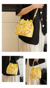 Detail of yellow bucket bag with fruit patch embroidery and adjustable shoulder strap