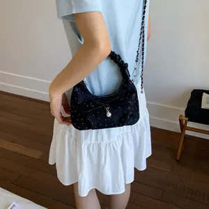 Black polka dot hobo bag with pearl pendant and pleated handle shown on model