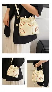 Detailed views of a cream bucket bag with orange citrus patches and drawstring closure