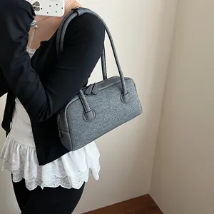 Dark gray denim Boston bag with white stitching and shoulder straps in a minimalist style
