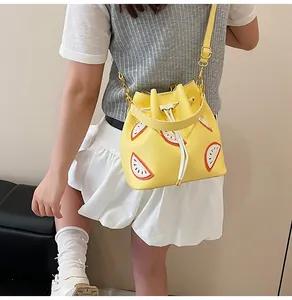 Detailed view of yellow fruit-patterned bucket bag with adjustable shoulder strap and drawstring