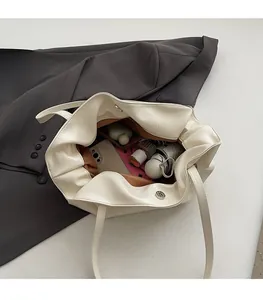 Spacious interior of beige pleated leather tote bag with magnetic closure and items