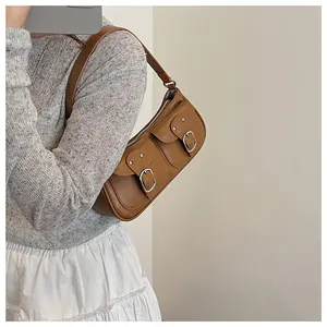 Detalle del bolso de hombro en cuero marrón con hebillas vintage y bolsillos de solapa