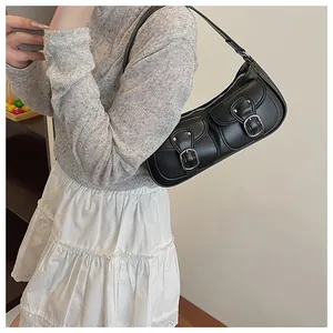 Detalle del bolso de hombro de cuero negro con bolsillos y hebillas plateadas