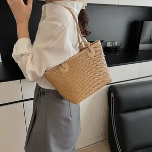 Elegant beige woven leather tote bag with slim shoulder straps shown on a model