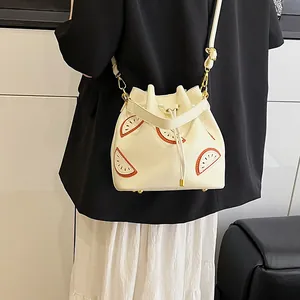 Chic cream-colored drawstring bucket bag with vibrant orange slice embroidery and gold hardware