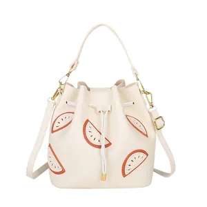 Cream white drawstring bucket bag with orange fruit slice appliques and shoulder strap