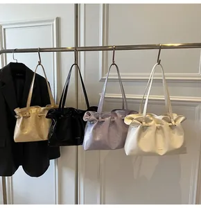 Detail of glossy pleated tote bags in champagne, black, purple, and white colors
