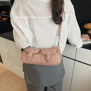 Bolso bandolera de cuero rosa con hebillas plateadas llevado por una modelo de moda