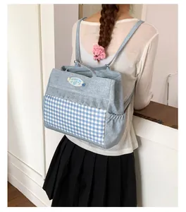 Détail du sac à dos bleu clair avec motif à carreaux, bords volantés et texture denim